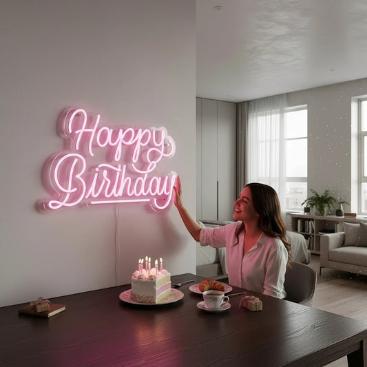 Lux Neon pink cursive "Happy Birthday" neon sign mounted on a white wall above a birthday cake.