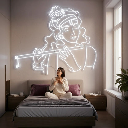 Lux Neon Krishna neon sign with flute, white outline, above a woman meditating on a bed.